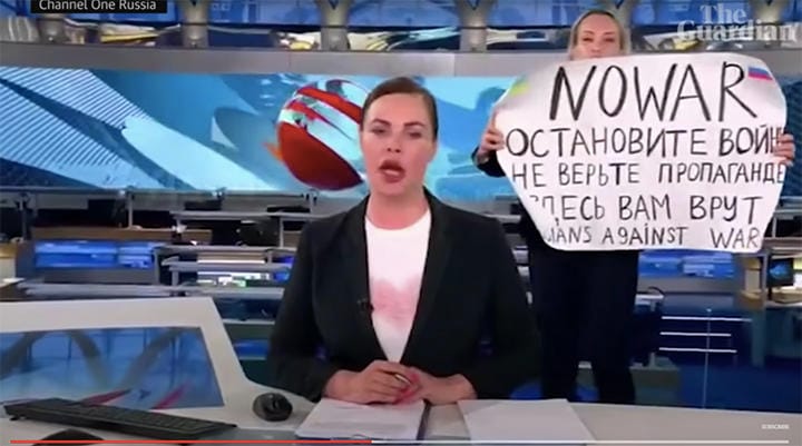 生放送中のスタジオで反戦メッセージを掲げた女性。映像は数秒で切り替わった　Guardian News-YouTube