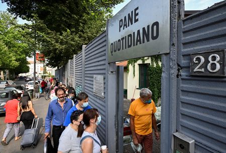 　アルプス山脈に近いイタリア北部のリゾート地でウエートレスをしていたディアナ・パリーニさん（４４）は先月、退職した。賃金と労働環境のひどさにうんざりしたからだ。写真はミラノで、食料の配給に並ぶ人々。１４日撮影（２０２２年　ロイター/Flavio Lo Scalzo）