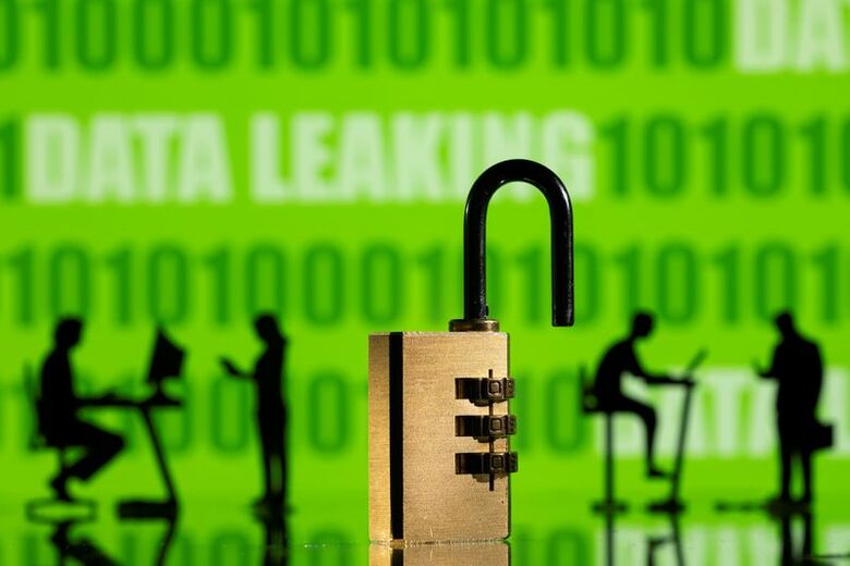 写真はバイナリーコードと「データ流出」の文字、南京錠とパソコンを操作する人々のイメージ。2022年2月撮影。REUTERS/Dado Ruvic