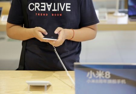 　１０月２４日、中国のスマートフォンメーカー、シャオミは、メモリー半導体の価格高騰により携帯端末の製造コストが上昇していると述べた。写真は、中国・北京のシャオミの店舗でスマートフォンを使用する顧客。２０１８年６月撮影（２０２５年　ロイター/Jason Lee）