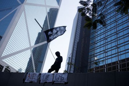 １２月４日、香港政府は４０億香港ドル（５億１１００万米ドル）規模の景気対策を新たに導入すると発表した。写真は１１月、香港中心部でデモ活動の旗を掲げる参加者（２０１９年　ロイター/Thomas Peter）