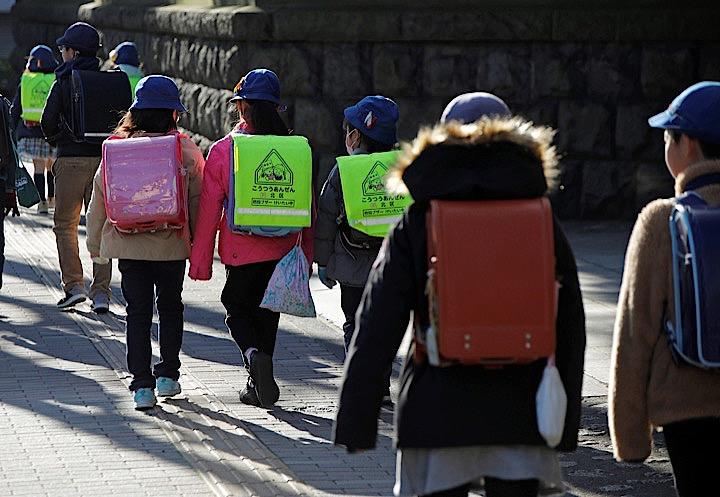 菅義偉官房長官は、新型コロナウイルスについて、まん延する恐れが高いものの、新学期から学校を再開する方針を変更する必要はないとの認識を示した。写真は小学校に登校する子供たち。2月末東京で。Issei Kato  - REUTERS