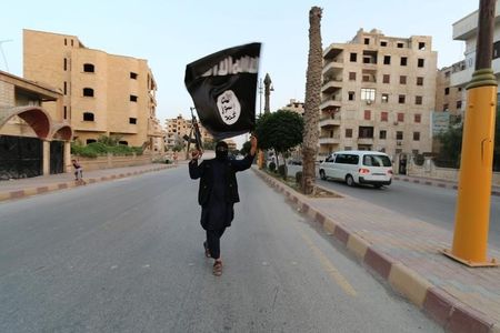 　１２月１０日、米財務省の高官は１０日、過激派組織「イスラム国」の原油取引が月４０００万ドルに上り、売却先は主にシリアのアサド政権で、一部がトルコ側にわたっていると指摘した。写真はイスラム国の旗を掲げる支持者。シリア北部ラッカで昨年６月撮影（２０１５年　ロイター）