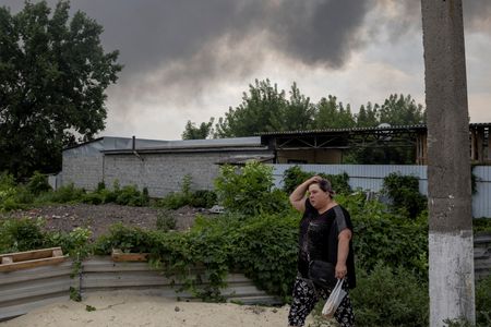 ７月５日、ウクライナ東部ルガンスク州のガイダイ知事は、ロシア軍が同州を制圧した後、激しい戦闘を展開して隣接するドネツク州に進軍していると述べた。写真はスラビャンスクで攻撃を受けた市場付近を歩く女性（２０２２年　ロイター/Marko Djurica）