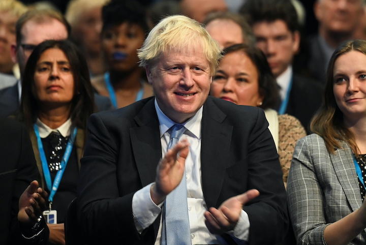 保守党大会でスナク財務省のスピーチに拍手するジョンソン首相（10月4日）　Toby Melville-REUTERS
