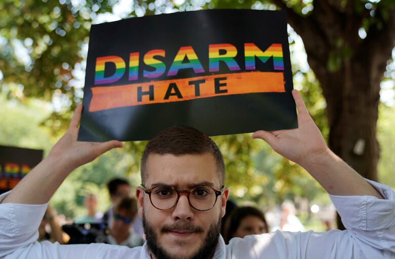 ホワイトハウス前でレインボーカラーのサインを掲げて白人至上主義に抗議する男性（8月6日）　Kevin Lamarque-REUTERS