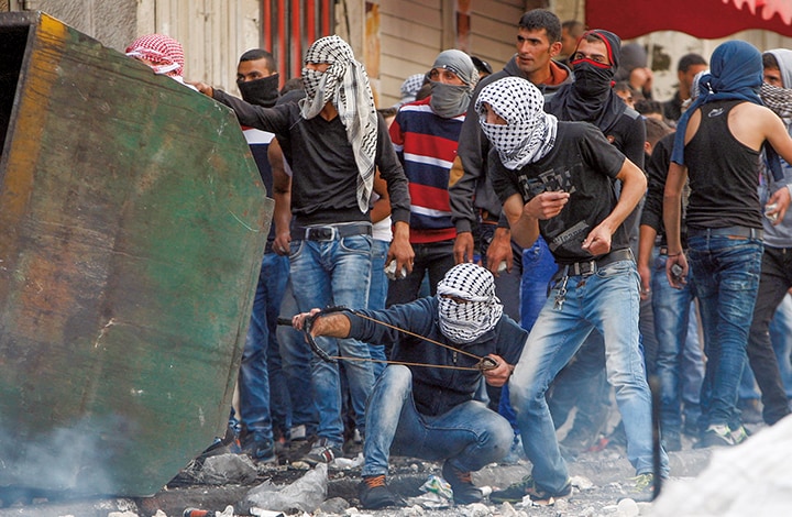 イスラエルの治安部隊に投石するパレスチナ人（ヨルダン川西岸地区ヘブロン）　Mussa Qawasma-REUTERS