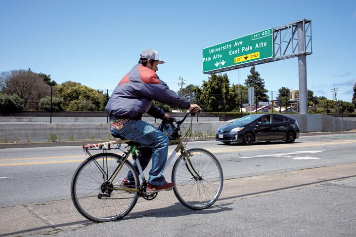 パロアルトの高速道路を走る自転車と自動車。標識には対照的な2つの街を分けるように走るユニバーシティー・アベニューの名が