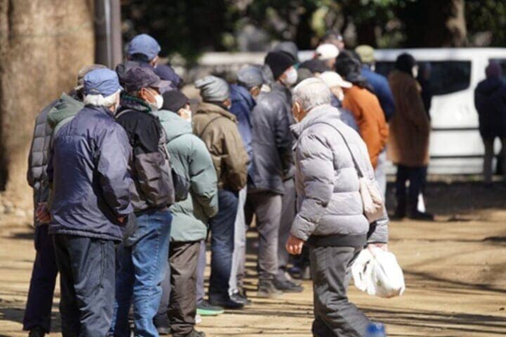 公園の吹き出しに並んで無料の食べ物を受け取るホームレスや生活貧困者たち
