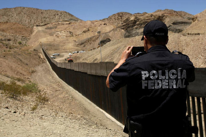 6月3日、メキシコのエブラルド外相は、米国が同国を「安全な第三国」に指定し、米国への難民申請者を移送してメキシコで保護するという案を米国側が提示しても拒否する考えを示した。写真は米国との国境のフェンスを撮影するメキシコの警察官。シウダー・ファレスで5月に撮影（2019年　ロイター／Jose Luis Gonzalez）