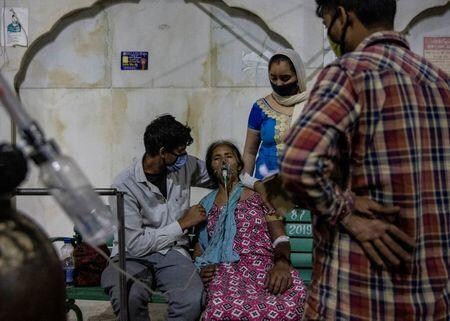 インドで新型コロナウイルスの新規感染者が世界最多を更新した。モディ首相は感染の「嵐」がインドを揺るがしていると述べ、全国民に対し感染対策やワクチン接種を呼び掛けた。写真はインドのガジアバードの寺院で提供された酸素を吸引する女性。２４日撮影（２０２１年　ロイター/Danish Siddiqui）