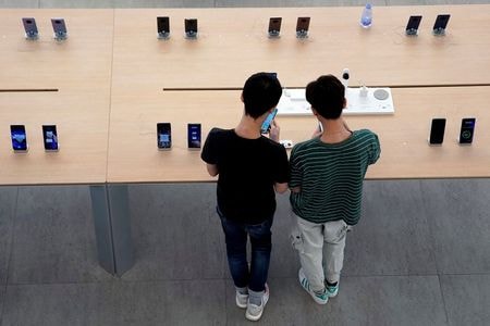　９月２２日、中国の政府系シンクタンク、中国情報通信研究院（ＣＡＩＣＴ）は、８月の国内スマートフォン出荷台数は前年同月比９．９％減の２３１０万台と発表した。写真は深センにあるファーウェイの店舗でスマートフォンを見る人々。２０１９年１０月撮影（２０２１年　ロイター/Aly Song）
