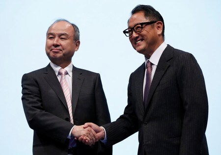 　１０月４日、トヨタ自動車とソフトバンクの２大企業が、モビリティサービスの構築に向けて初めて本格的に手を組んだ。写真は都内の記者会見場で握手を交わすトヨタの豊田章男社長（右）とソフトバンクグループの孫正義社長（２０１８年　ロイター/Issei Kato）