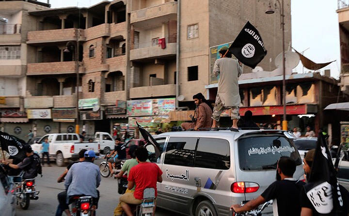 シリアのラッカでISISの旗を振る戦闘員（2014年）　REUTERS