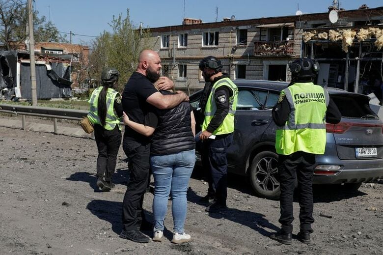 ロシアのミサイル攻撃により死亡した親族の遺体を乗せた車の横で悲しむ人たち。ウクライナ北東部ハルキウ州で４日撮影。REUTERS/Sofiia Gatilova