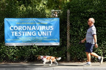 　３月４日、英イングランド公衆衛生局（ＰＨＥ）は、英国内で新型コロナウイルスの新たな変異株に感染した１６例を確認したと発表した。写真はロンドンで、検査の案内ポスターの前を横切る男性。２０２０年８月撮影（２０２１年　ロイター/Toby Melville）