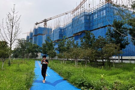 経営危機に陥っている中国不動産開発大手、碧桂園（カントリー・ガーデン）が、人民元建て債の返済延長の承認を債権者から得たことが、複数の関係者の話やロイターが確認した文書で分かった。写真は中国・北京で碧桂園の住宅建設現場を通り過ぎる人。８月撮影（２０２３年　ロイター／Tingshu Wang）