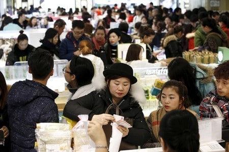 　１１月２８日、中国政府は、北京と山東の旅行会社に対して、韓国への団体旅行の販売再開を認めると明らかにした。写真は２０１６年２月、ソウルのロッテ免税店で現金を支払う中国人旅行者たち（２０１７年　ロイター／Kim Hong-Ji）