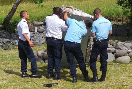 ７月３０日、マレーシアの副運輸相はインド洋のフランス領レユニオン島で見つかった飛行機の残骸について、ボーイング７７７型機の一部であることは「ほぼ確実」だと述べた。写真は２９日、レユニオン島で発見された飛行機の残骸を調べる仏警察官ら（２０１５年　ロイター/Zinfos974/Prisca Bigot）