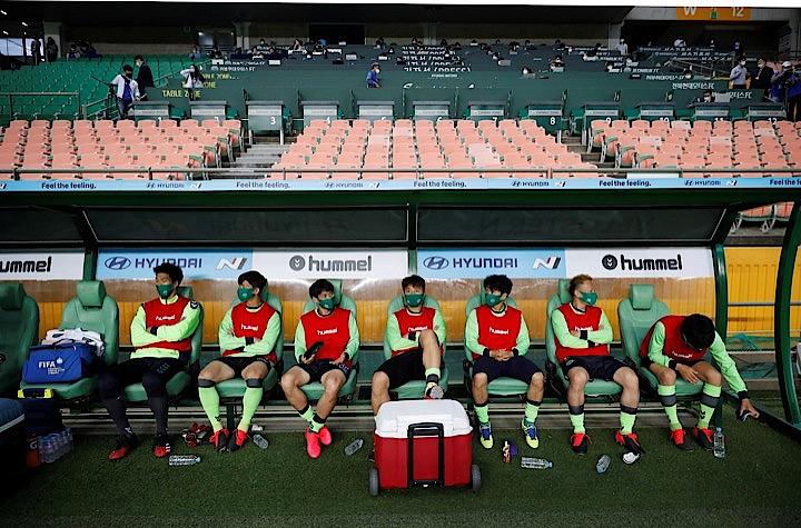 韓国では新型コロナへの規制が緩和され、野球やサッカーなども無観客でリーグ戦が開幕。 ただし練習や試合以外は常にマスクの着用が義務づけられている。写真は5月8日全州で行われた全北現代モータースと水原三星ブルーウィングスの試合前のようす。KIM HONG-JI / REUTERS