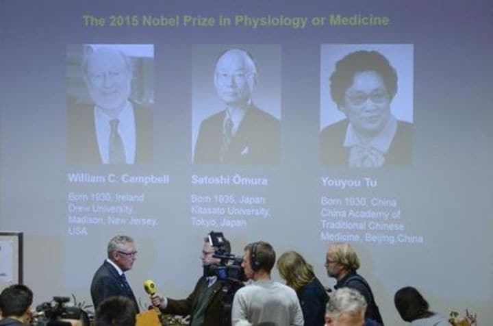 １０月５日、今年のノーベル医学生理学賞に北里大学名誉教授の大村智氏（８０）ら３人が選ばれた。写真はスウェーデンのカロリンスカ研究所で発表された今回の受賞者３名のスライドの前で、インタビューを受ける同関係者。提供写真（２０１５年　ロイター/Fredrik Sandberg/TT News Agency）