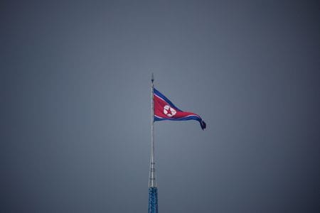 　日本政府は３日朝、北朝鮮から弾道ミサイルが発射された可能性があると発表した。ミサイルは午前７時４８分ごろ日本の上空を通過して太平洋へ通過したものとみられるとし、海上保安庁は同８時１０分、既に落下したもようとの情報を出した。写真は北朝鮮の旗。板門店付近で７月代表撮影（２０２２年　ロイター）