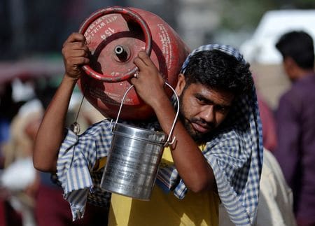 デリーの旧市街にある卸売市場で、LPGボンベを肩に担ぐ男性。2023年6月撮影。REUTERS/Anushree Fadnavis