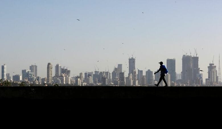 ムンバイ中心部の金融街を望む壁沿いを歩く男性。2017年3月、ムンバイで撮影。REUTERS/Danish Siddiqui