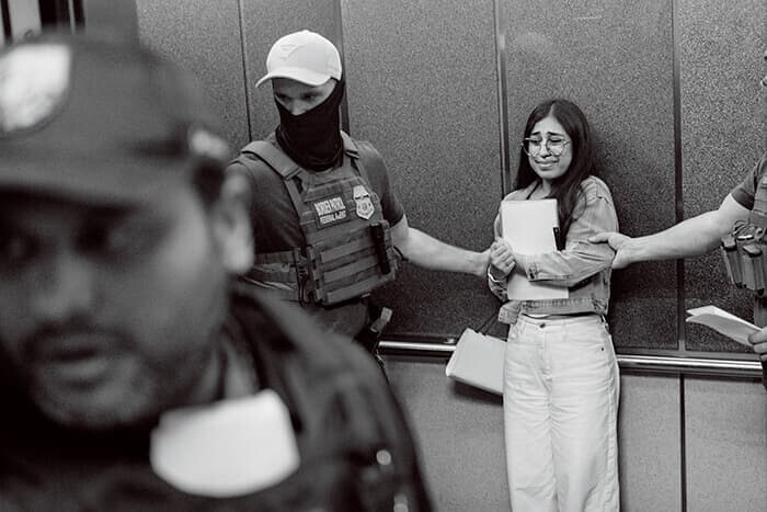 捜査官に腕をつかまれエレベーターに乗せられる移民。拘束後は遠隔地の収容施設に送られる可能性が高い