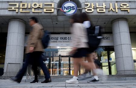 　３月２５日、世界第３位の公的年金である韓国の国営年金基金「国民年金公団」は、不安定なウォン相場を安定させるため、長期的に戦略的ヘッジ比率を引き上げる方針だ。写真は国民年金公団（ＮＰＳ）の支店前を歩く人々。ソウルで２０１６年１１月撮影（２０２６年　ロイター/Kim Hong-Ji）