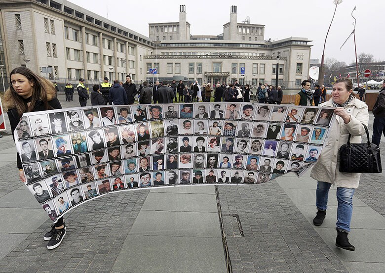 判決を前に法廷で犠牲者の写真を掲げるボスニアの人たち　Michael Kooren-REUTERS