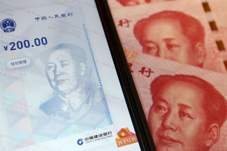 中国人民銀行（中央銀行）は９日、人民元の対ドル基準値を２０１８年６月２８日以来の元高水準に設定した。写真イラストは人民元紙幣とスマートフォンに表示したデジタル人民元の画像を組み合わせた。今年１０月１６日に撮影。（２０２０年　ロイター／Florence Lo）
