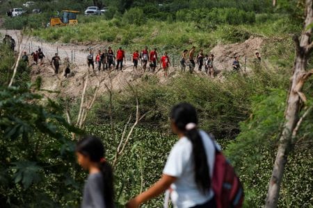 　５月１２日、米国では移民流入制限措置「タイトル４２」に代わる入国管理体制が敷かれた。写真は川を渡って米国に移動した移民ら。メキシコ側から１１日撮影（２０２３年　ロイター／Daniel Becerril）