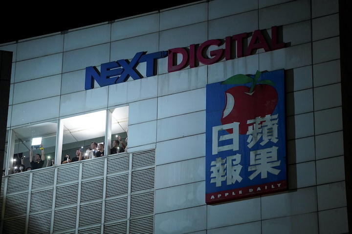 廃刊が決まり、外の支持者たちにスマホのライトを振るリンゴ日報のスタッフ（6月23日）　 Lam Yik-REUTERS