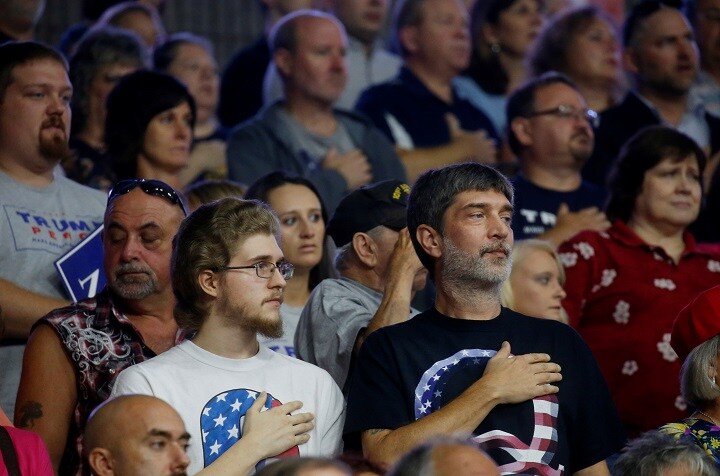 トランプの選挙集会で「QAnon」のロゴに手をあてて国家を歌うトランプ支持者（8月21日）　Leah Millis-REUTERS