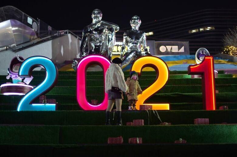 2021年は中国にとって極めて重要な年だ。共産党結成100周年、かつ第14次5カ年計画の開始年でもある。写真は北京のショッピングセンターの飾りの前に立つ親子。12月23日撮影（2021年　ロイター/Tingshu Wang）