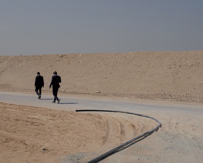 ドバイに隣接するシャルジャ首長国で水道パイプラインをまたぎ建設現場を歩くビジネスマン。水資源に乏しいUAEは脱塩処理で淡水化した海水に依存している