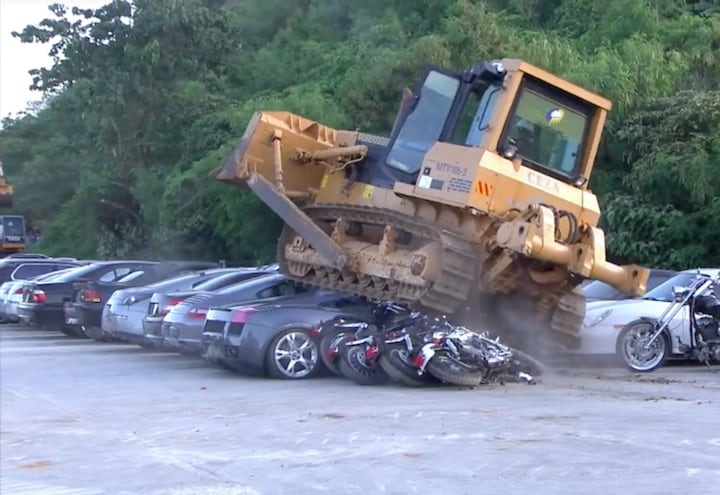 オートバイの奥でブルドーザーに押しつぶされているのはランボルギーニ。もったいない……。(c) フィリピン大統領府