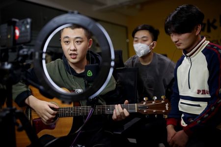 Musicians from the Chinese group \"The 2econd\" Zhang Cheng, Zhuang Fei and Wen Zheng, perform for their fans during a live-streaming session broadcast on the video sharing website Bilibili at an office in Beijing, China, March 14, 2020. \"I see this period