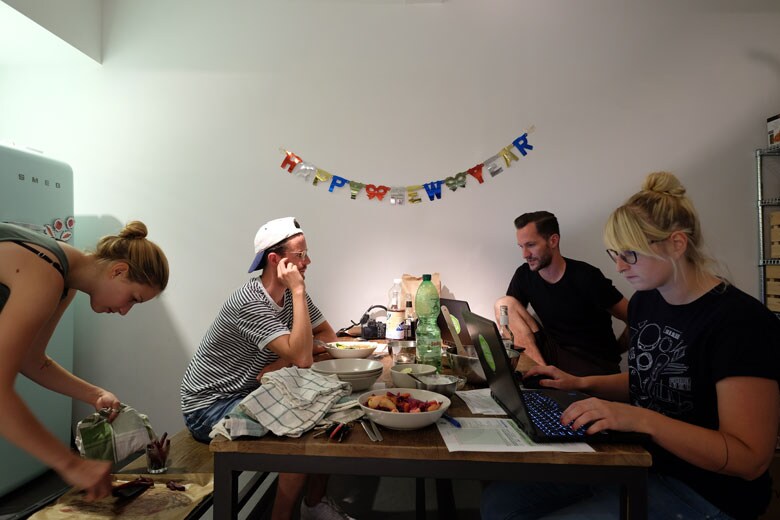 同じくキッチンスペース。正月に向けた新しいレシピを開発するための会議が行われている。壁の「HAPPY NEW YEAR」は、正月の雰囲気を出すために飾り付けられたもの。　WORKSIGHT