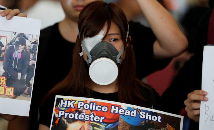 警官に片目を傷つけられた同志との連帯を表す眼帯をして戦うデモ隊（8月12日、香港国際空港）　Issei Kato-REUTERS