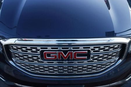 A badge of GMC, an automobile brand owned by General Motors Company, is seen on the grill of a vehicle for sale at a car dealership in Queens, New York, U.S., November 16, 2021. REUTERS/Andrew Kelly