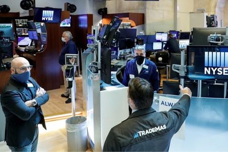 FILE PHOTO: Traders wearing masks work, on the first day of in person trading since the closure during the outbreak of the coronavirus disease (COVID-19) on the floor at the New York Stock Exchange (NYSE) in New York, U.S., May 26, 2020. REUTERS/Brendan M