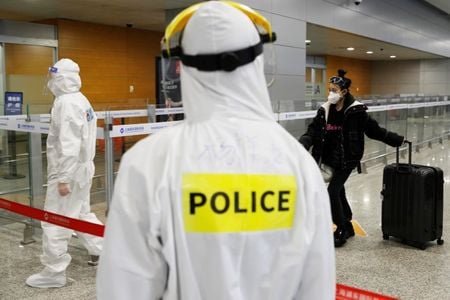 中国当局は新型コロナウイルスの感染者数について、海外から持ち込まれたケースが２０日に過去最大になったと発表した。写真は上海空港の到着ゲートに立つ警察官。３月２０日撮影（２０２０年　ロイタ/cnsphoto）