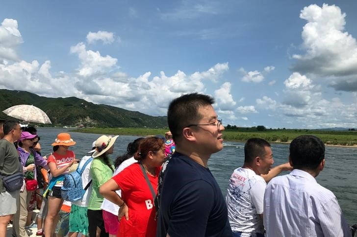 １１月７日、北朝鮮との国境にある中国・遼寧省丹東市の旅行会社は、北朝鮮の首都・平壌などを訪れる旅行を８日から中止するよう当局から指示を受けた。写真は丹東でボートに乗る中国人観光客。８月撮影（２０１７年　ロイター/Philip Wen）