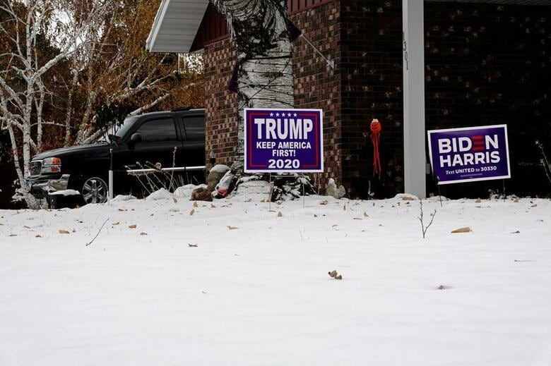ロイター/イプソスの最新調査によると、米大統領選で現職のトランプ大統領と野党・民主党候補のバイデン前副大統領をそれぞれ支持する人の4割強は、自分が推す候補が敗北した場合選挙結果を受け入れないと答えた。写真はトランプ氏とバイデン氏を支持するサイン。ノースダコタ州ファーゴの住宅で25日撮影(2020年　ロイター/Bing Guan)