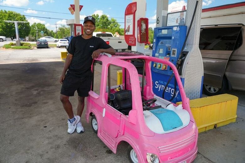 米ジョージア州エレンウッドのガソリンスタンドで、自作のガソリン節約グッズであるおもちゃの車とポーズを取るマリ・ハイタワーさん（30）。5月18日撮影。REUTERS/Jayla Whitfield-Anderson