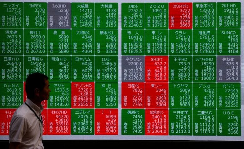 株価掲示板の前を通り過ぎる男性。東京都内で26年6月撮影。REUTERS/Manami Yamada
