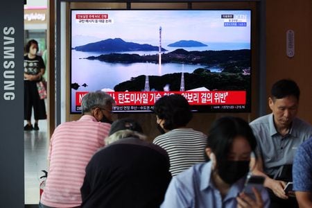　１０月１０日、北朝鮮は、米国による核先制攻撃能力向上や「世界の覇権」確保を目的とする宇宙の軍事化に対抗するため、軍事偵察衛星の運用が不可欠との見解を表明した。写真は北朝鮮による宇宙ロケット発射のＴＶニュースをみる人々。韓国ソウルの駅で８月撮影（２０２３年　ロイター／Kim Hong-Ji）