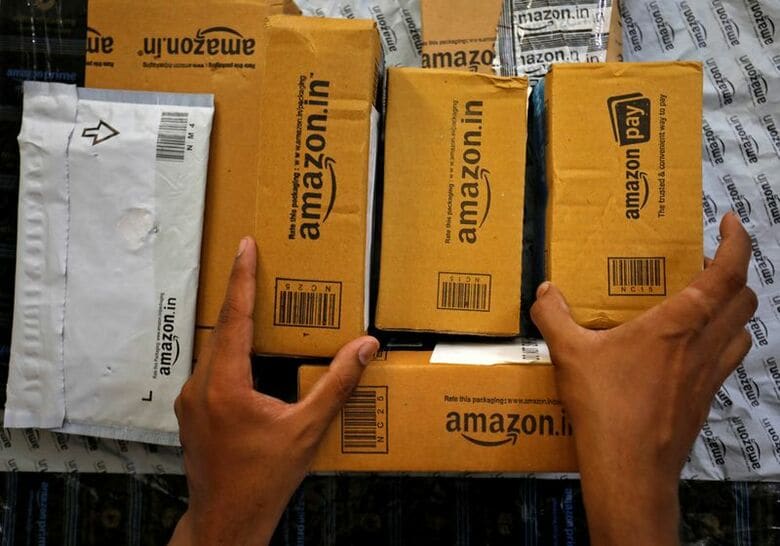 インド西部アーメダバードにあるアマゾンの施設前で、配達用の荷物を車両内で仕分けする作業員。2021年3月、アーメダバードで撮影。REUTERS/Amit Dave